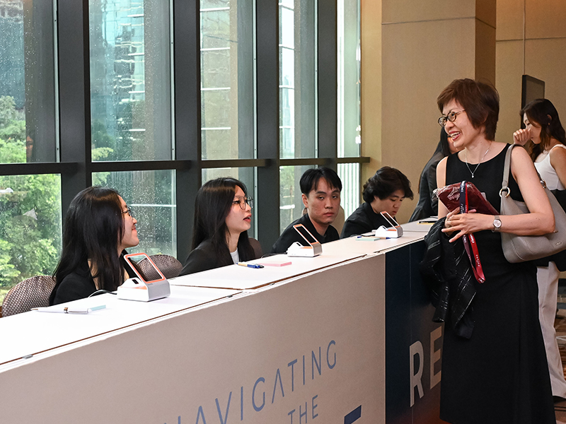 Onsite registration counter with check-in crew welcoming an arriving guest at a Malaysian corporate event.